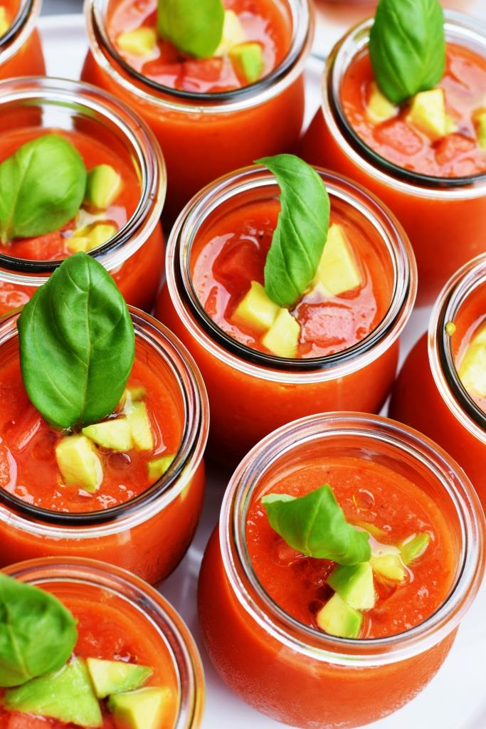 Sommerliche Wassermelonen-Gazpacho im Glas, garniert mit Avocado- und Melonenwürfeln