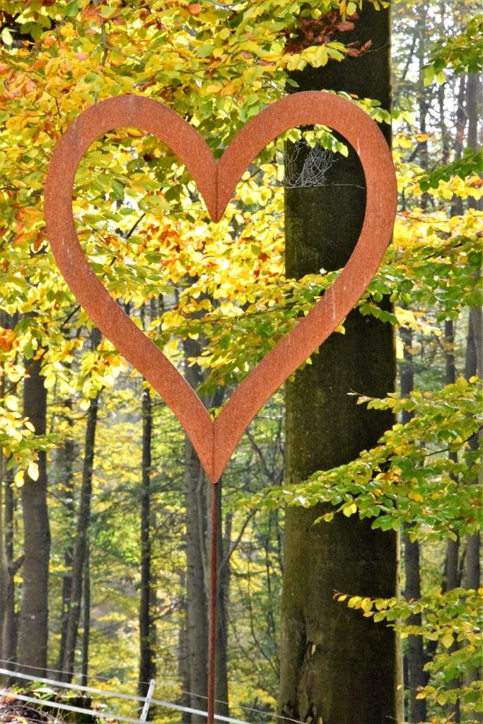 I LOVE FALL - rostiges Herz auf Eisenstab vor dem Herbstwald