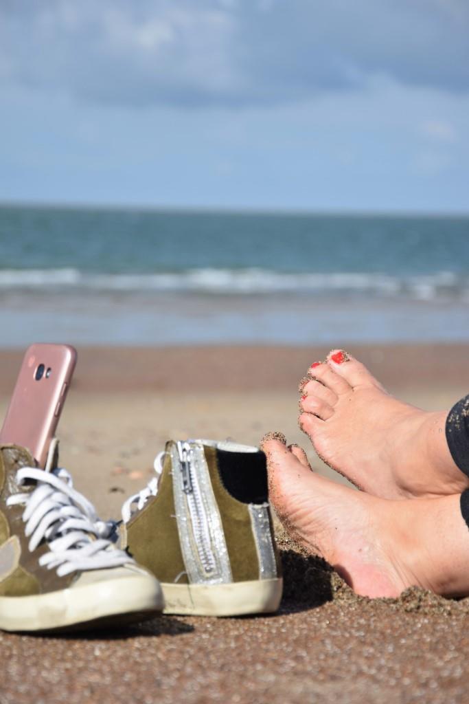 Einfach mal Pause machen am Strand. Schuhe aus, Füße in den Sand, Handy auf Offline