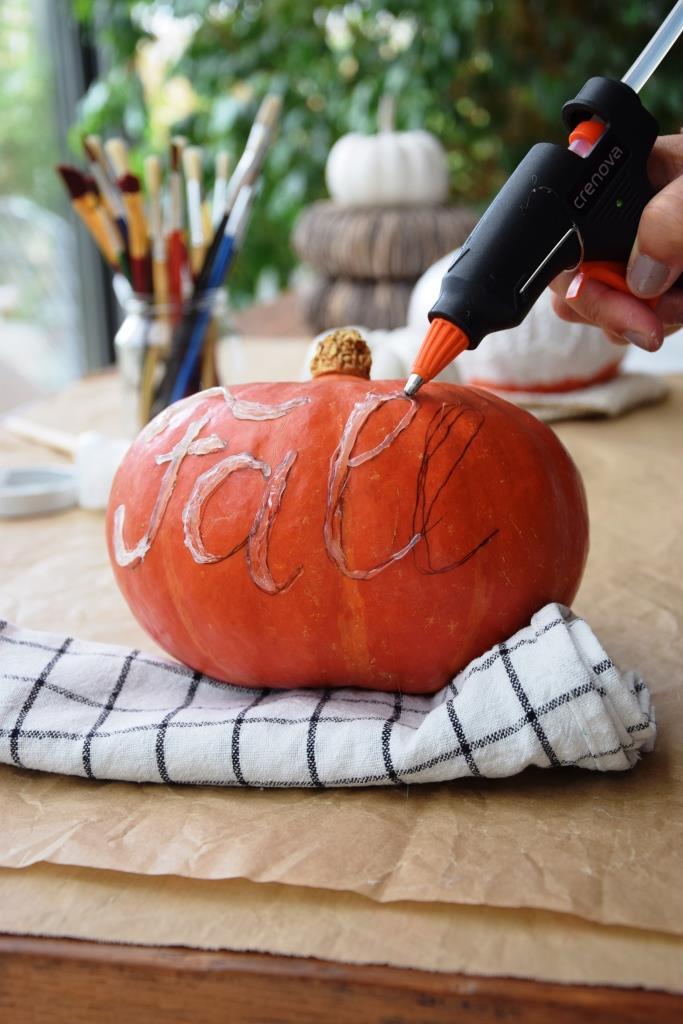 Ein Lettering aus der Heißklebepistole auf dem Kürbis
