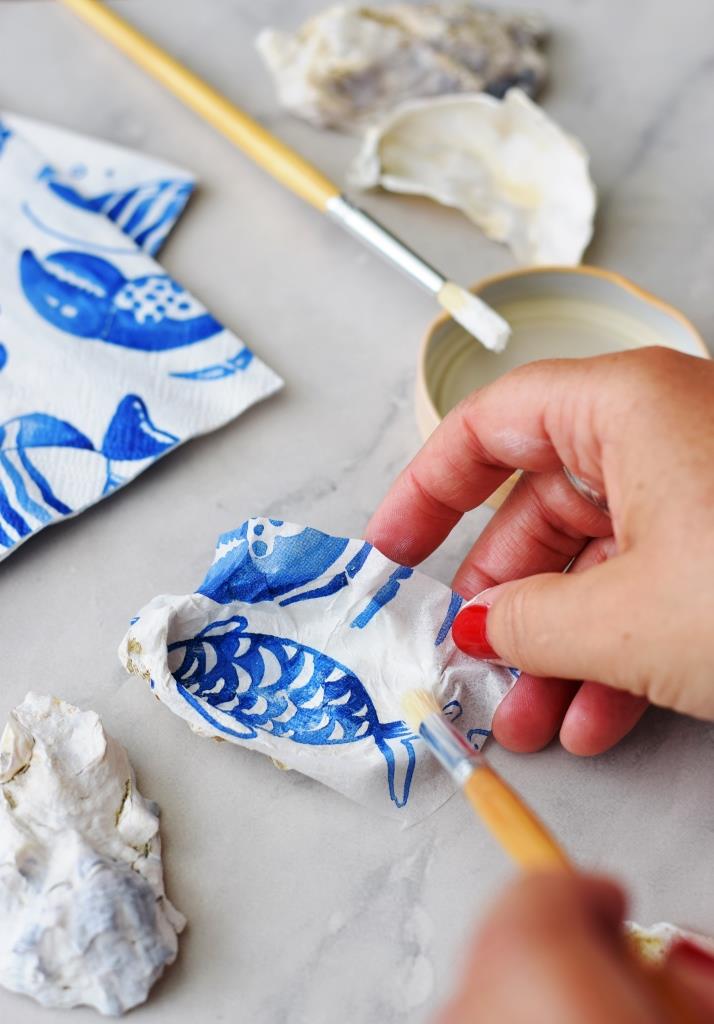 Das Stück Serviette wird mit einem weichen Pinsel vorsichtig in die Auster gestrichen