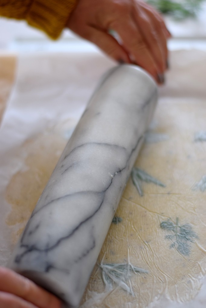 Mit der Nudelrolle werden die Kräuter mit dem Teig verbunden